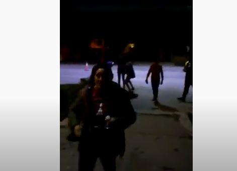 Captura de video, mujer rocia con alcohol la puerta de una comisaría