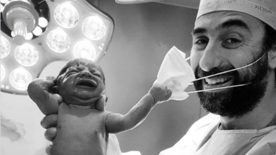 Un bebé sostiene la mascarilla de un médico al nacer.
